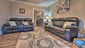 Ein Wohnzimmer mit zwei Ledersofas, einem gemusterten Teppich und einem Deckenventilator.
