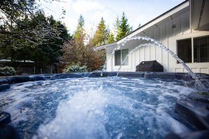 A hot tub with water jets, surrounded by trees and a building.