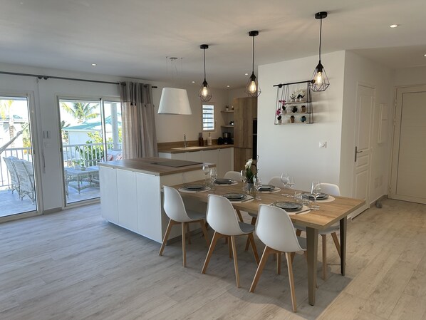 A modern kitchen with a central island, white cabinetry, and pendant lighting. - Orient Bay, Appartement Luxueux à 3 Minutes de la Plage! (Collectivité de Saint-Martin)