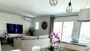 En matplats med ett träbord dukat för sex personer, vita stolar och en tv-apparat i bakgrunden.