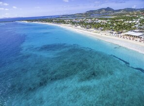 A coastal resort with a beach, clear turquoise waters, and a backdrop of hills. - Orient Bay, Appartement Luxueux à 3 Minutes de la Plage! (Collectivité de Saint-Martin)