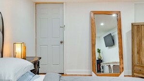A bedroom with a bed, dresser, mirror, and a television on the wall. - Lovely Elmont Apartment - Walk to Bus Stop! (Elmont)