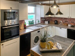 A modern kitchen with stainless steel appliances, a sink, and a countertop with a plant and bananas.