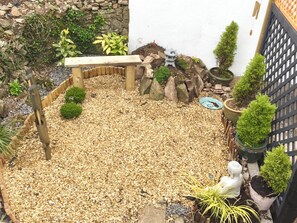 A garden with a wooden bench, a small pagoda, and various potted plants.