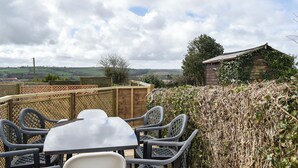 An outdoor dining area with a table and chairs, surrounded by a wooden fence and a hedge. - Only 4 miles from Westward Ho. (Littleham, near Bideford)