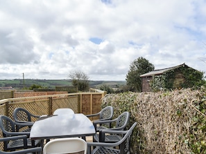 An outdoor dining area with a table and chairs, surrounded by a wooden fence and a hedge. - Only 4 miles from Westward Ho. (Littleham, near Bideford)