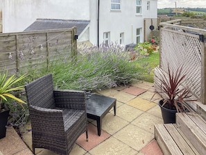 A patio with wicker furniture, a small table, and potted plants.