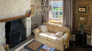 A cozy living room with a fireplace, a sofa, a coffee table with a chessboard, and a stone wall. - Only 4 miles from Westward Ho. (Littleham, near Bideford)