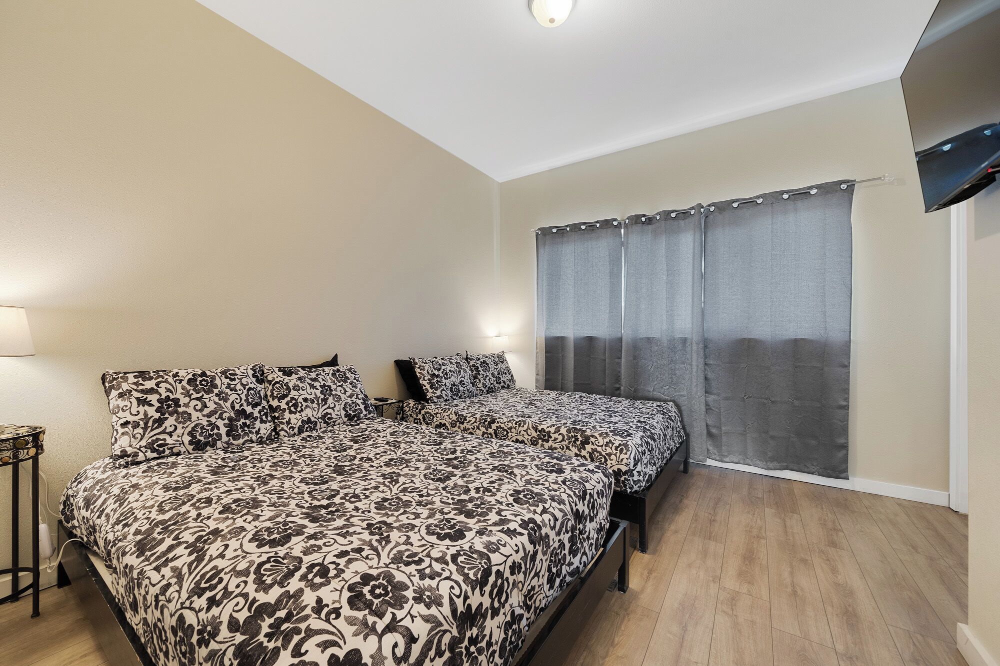 A bedroom with a bed, a bedside table, a lamp, and a window with curtains.