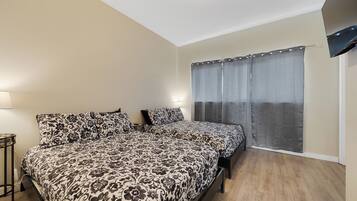A bedroom with a bed, a bedside table, a lamp, and a window with curtains.