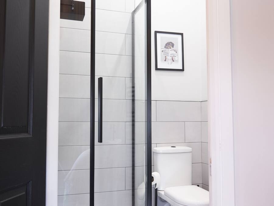 A modern bathroom with a glass shower enclosure, a toilet, and a framed picture on the wall.