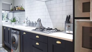 A modern kitchen with a built-in washer, a gas stove, and a coffee machine. - Home at Tancred Road  (Liverpool)