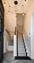 Una escalera con escalones blancos y peldaños negros que lleva a un rellano con una puerta negra.