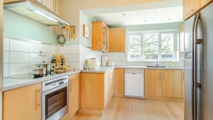 Una cucina moderna con mobili in legno, elettrodomestici in acciaio inossidabile e una finestra che fa entrare luce naturale.