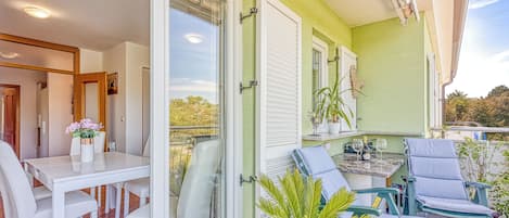 Un balcón con mesa y sillas para comer, una planta en maceta y una zona de estar con una mesa y sillas.