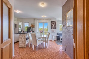 Un vaste espace de vie comprenant un coin repas avec une table et des chaises, un canapé et une cuisine avec un mur d’accent en pierre.