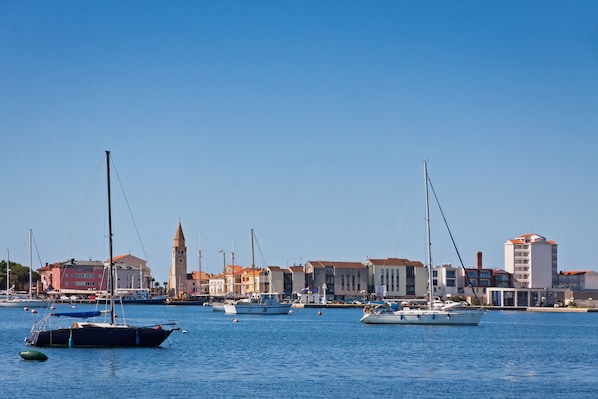 A marina with boats, a clock tower, and buildings with red roofs. - Sea Breeze Residence Mariella (Umag)