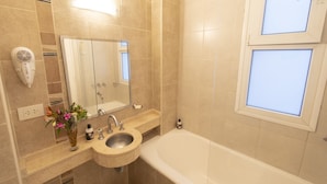Un baño con lavamanos, espejo y bañera.