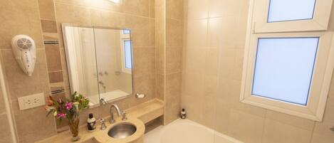 A bathroom with a sink, mirror, and bathtub.