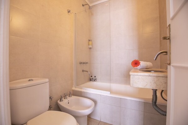 Un baño con inodoro, bidé, bañera y lavabo.
