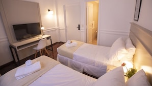 Habitación de hotel con dos camas, un escritorio, una silla y una televisión.