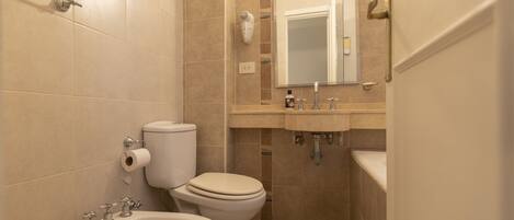A bathroom with a toilet, bidet, sink, and mirror.