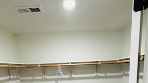 Ein Zimmer mit beigem Teppich, einem hölzernen Kleiderständer und einer weißen Tür.