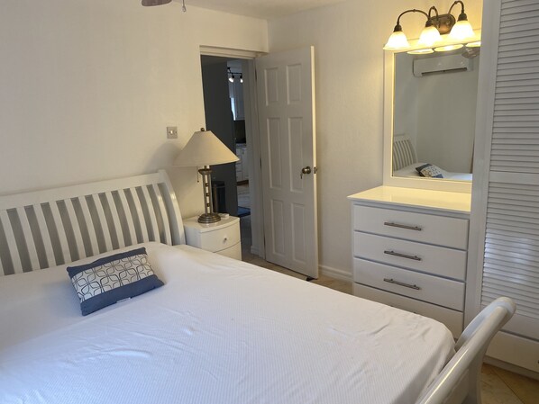 Une chambre à coucher comprenant un lit, une table de chevet, une lampe, une commode et un miroir.