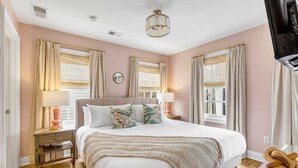 Une chambre à coucher avec un grand lit, des lampes de chevet, une table de chevet et une fenêtre avec des rideaux.