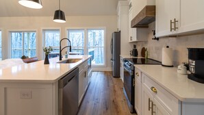 Een moderne keuken met witte kasten, roestvrijstalen apparatuur en hanglampen.