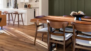 Een moderne keuken met witte kastjes, een houten eettafel en een kroonluchter.
