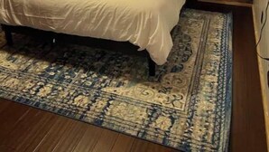 Een slaapkamer in chaletstijl met een bed, een raam met gordijnen en wandlampen.