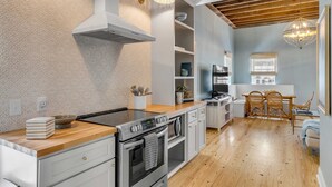 Una cocina moderna con encimera de madera, horno empotrado y muebles blancos.