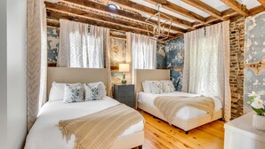 Un dormitorio con dos camas, suelo de madera y paredes de ladrillo visto.