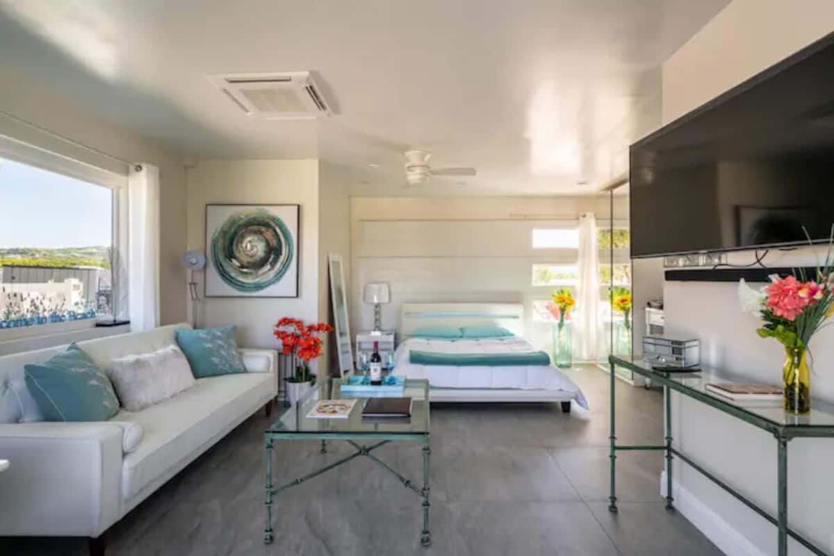 Une chambre moderne avec un lit, une table basse en verre et un téléviseur.