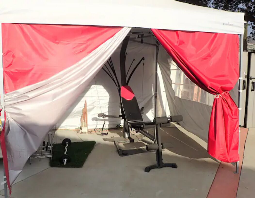 A tent with a bench and weights inside.