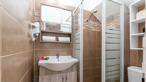 Ein modernes Badezimmer mit Duschkabine aus Glas, einem weißen Waschbecken und einem Spiegel darüber.