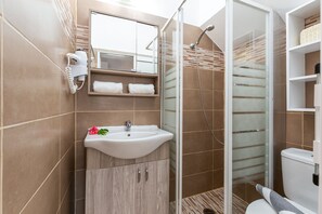 Deluxe studio suite | Badkamer | Een douche, een regendouche, een haardroger, handdoeken