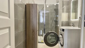 A modern bathroom with a glass shower enclosure, a built-in washing machine, and a toilet. - 5 minutes to Versailles (Saint-Cyr-l'École)