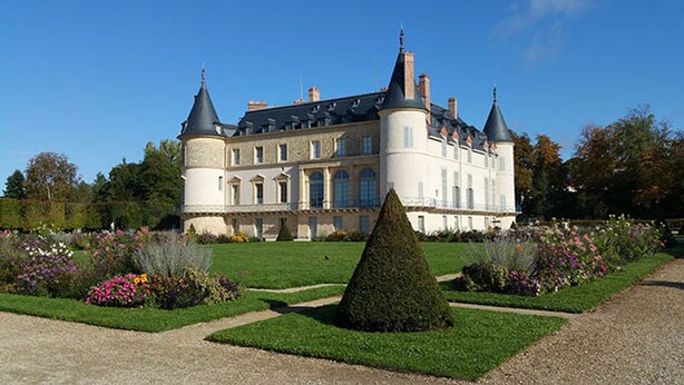 A large, historic building with multiple towers and a well-maintained garden with various plants and a central topiary. - 5 minutes to Versailles (Saint-Cyr-l'École)