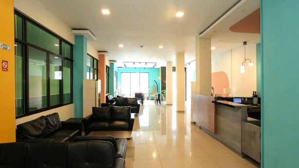 A modern hotel lobby with a reception desk, leather seating area, and a bright, spacious interior.