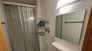 Ein Badezimmer mit Dusche, Toilette, Waschbecken und Spiegel.