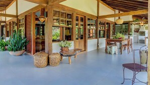 A spacious indoor area with wooden beams, large windows, and a dining table with chairs. - Casa OluOlu Itacaré (Itacaré)