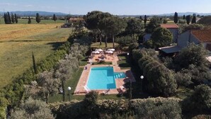 Ein großer rechteckiger Pool, umgeben von einem Garten mit Bäumen und einigen Sonnenschirmen.