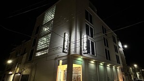 A hotel with a modern design, featuring large windows and a prominent neon sign. - Hotel Maricela (San Juan de los Lagos)