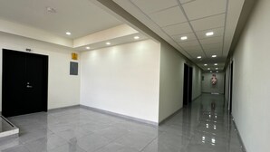 A clean, well-lit hallway with a tiled floor, a black door labeled '212', and a fire extinguisher mounted on the wall. - Hotel Maricela (San Juan de los Lagos)