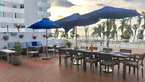 An outdoor patio with tables and chairs, umbrellas, and potted plants. - MB2E-Unique Terrace Two Bedrooms-Pool & Ocean View (Carolina)