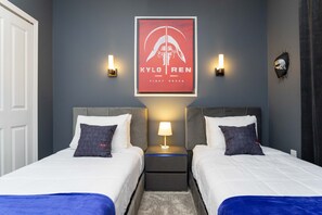 A hotel room with two beds, a nightstand with a lamp, and a wall-mounted artwork.