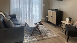 Una sala de estar moderna con un sofá, una mesa de centro, televisor y un mueble.