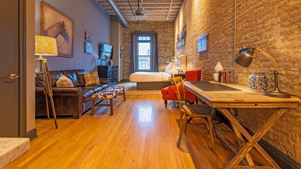 A room with a bed, a desk, a chair, a sofa, and a lamp. - 124 Lofts #2 - Downtown Dundee - Walk to Dining (West Dundee)